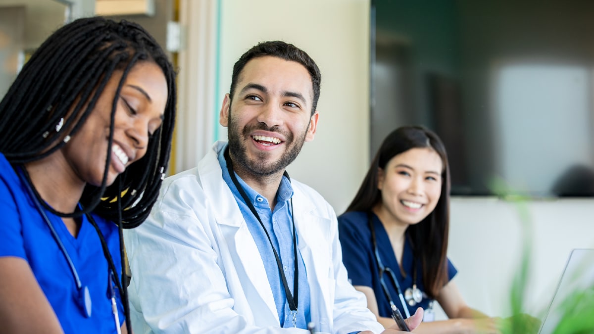 Three doctors sitting at a table smiling