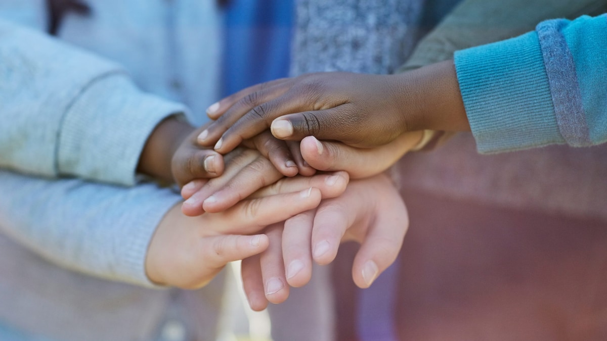 Five diverse hands stacked on top of each other