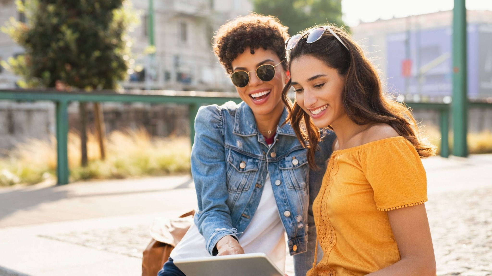 Two young women of reproductive age smile looking at a tablet.