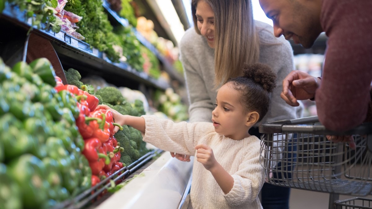 a mother, father, and child buying fresh vegetables