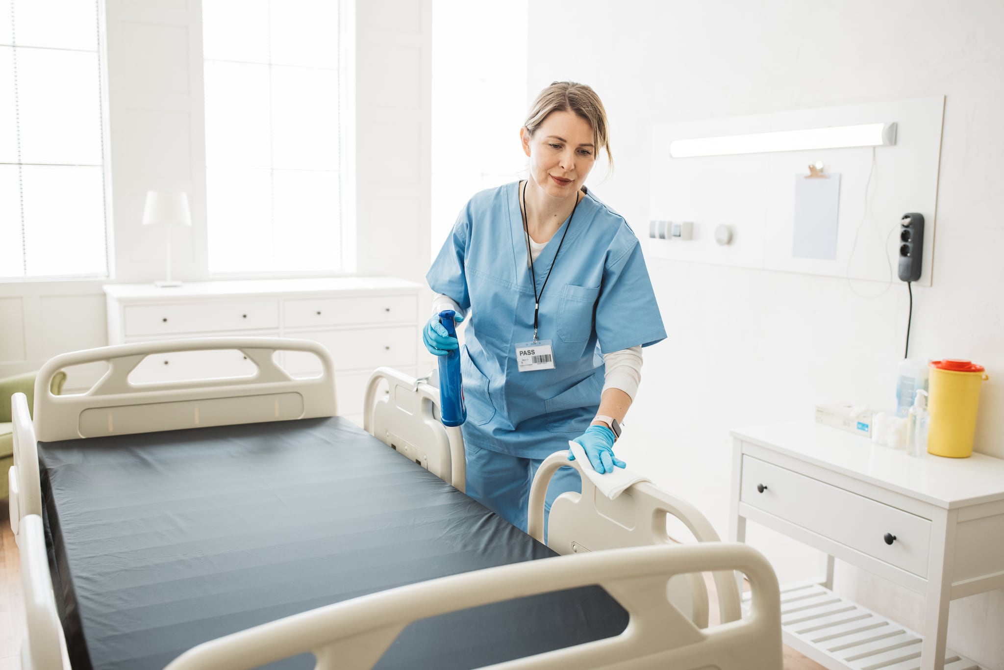 Hospital worker cleaning a hospital bed.