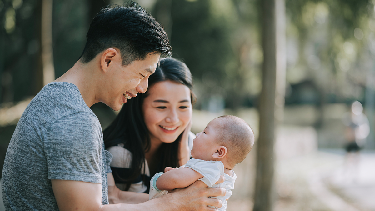 Dad and mother holding their baby and smiling