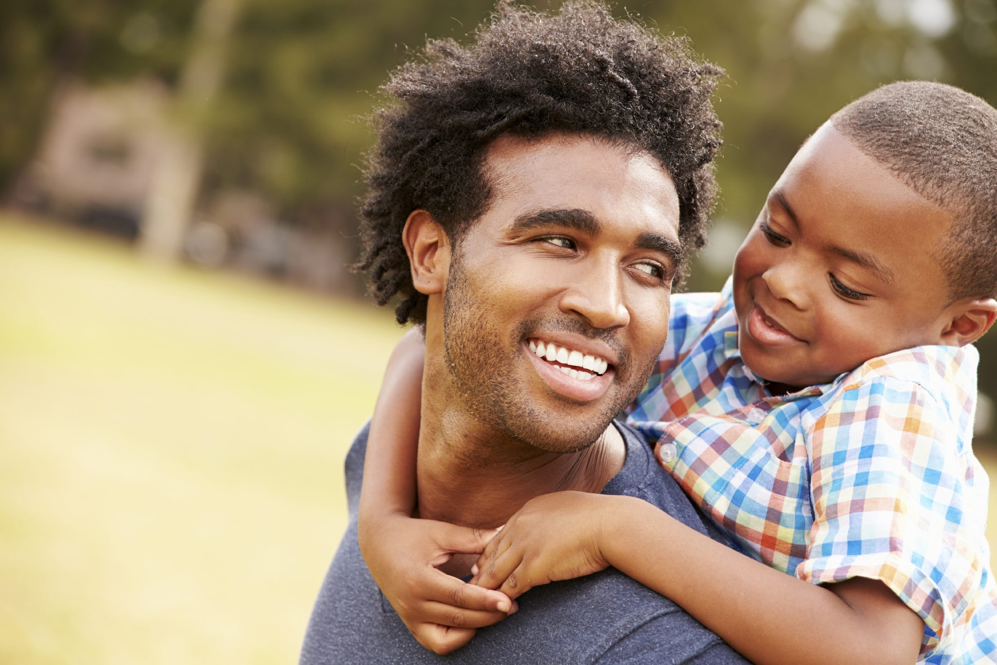 father giving son piggyback ride in the park