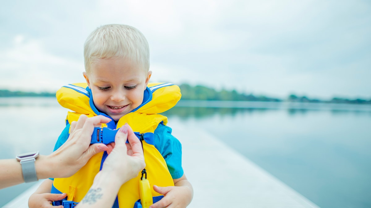 kid wearing life vest getting help putting it on