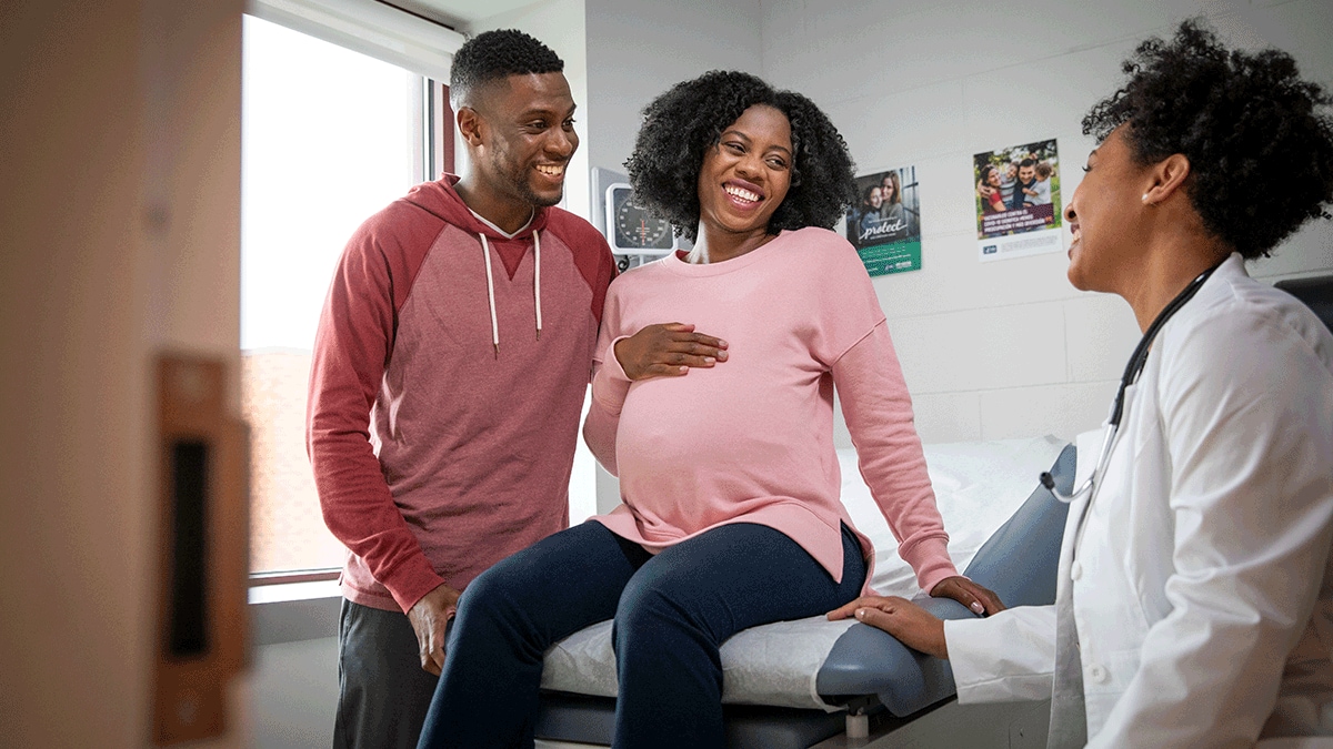 Young Black family - dad and pregnant mom at the doctor's office, smiling