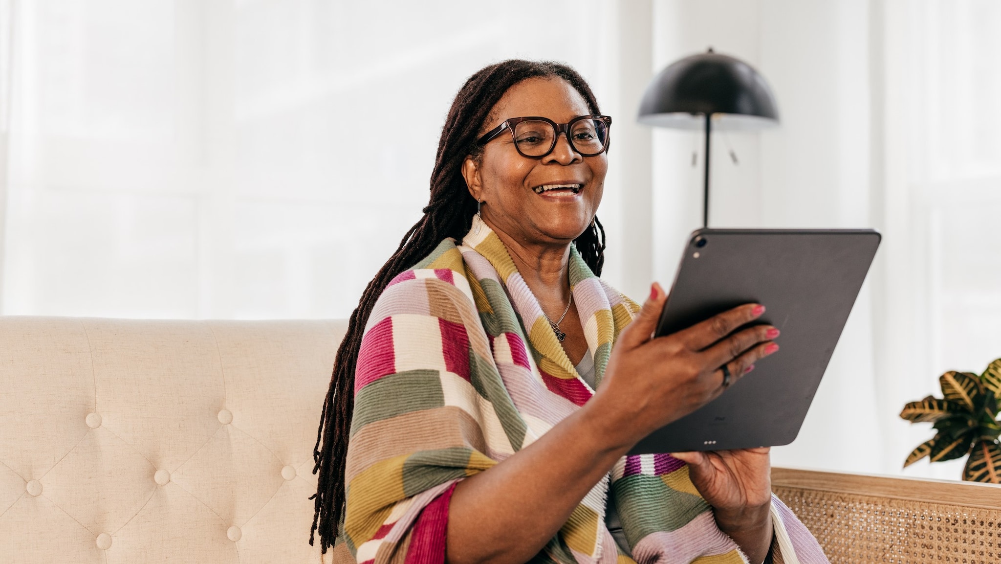 Senior woman holding a computer tablet connecting with her health care provider via telehealth