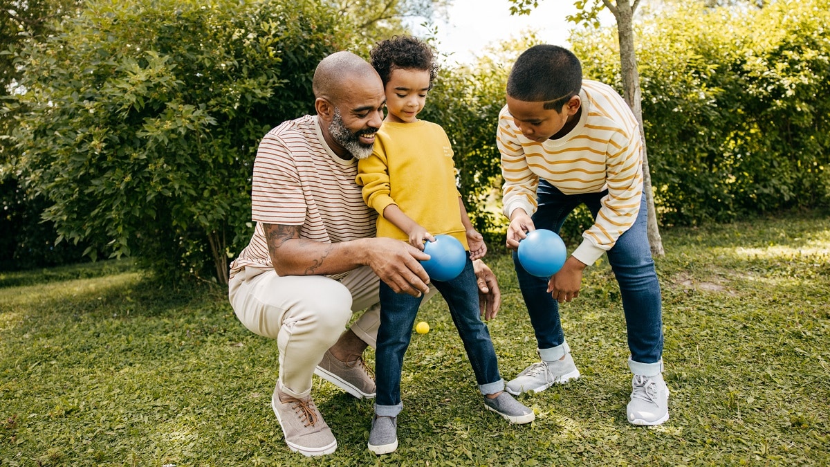 Father playing outside with two sons.