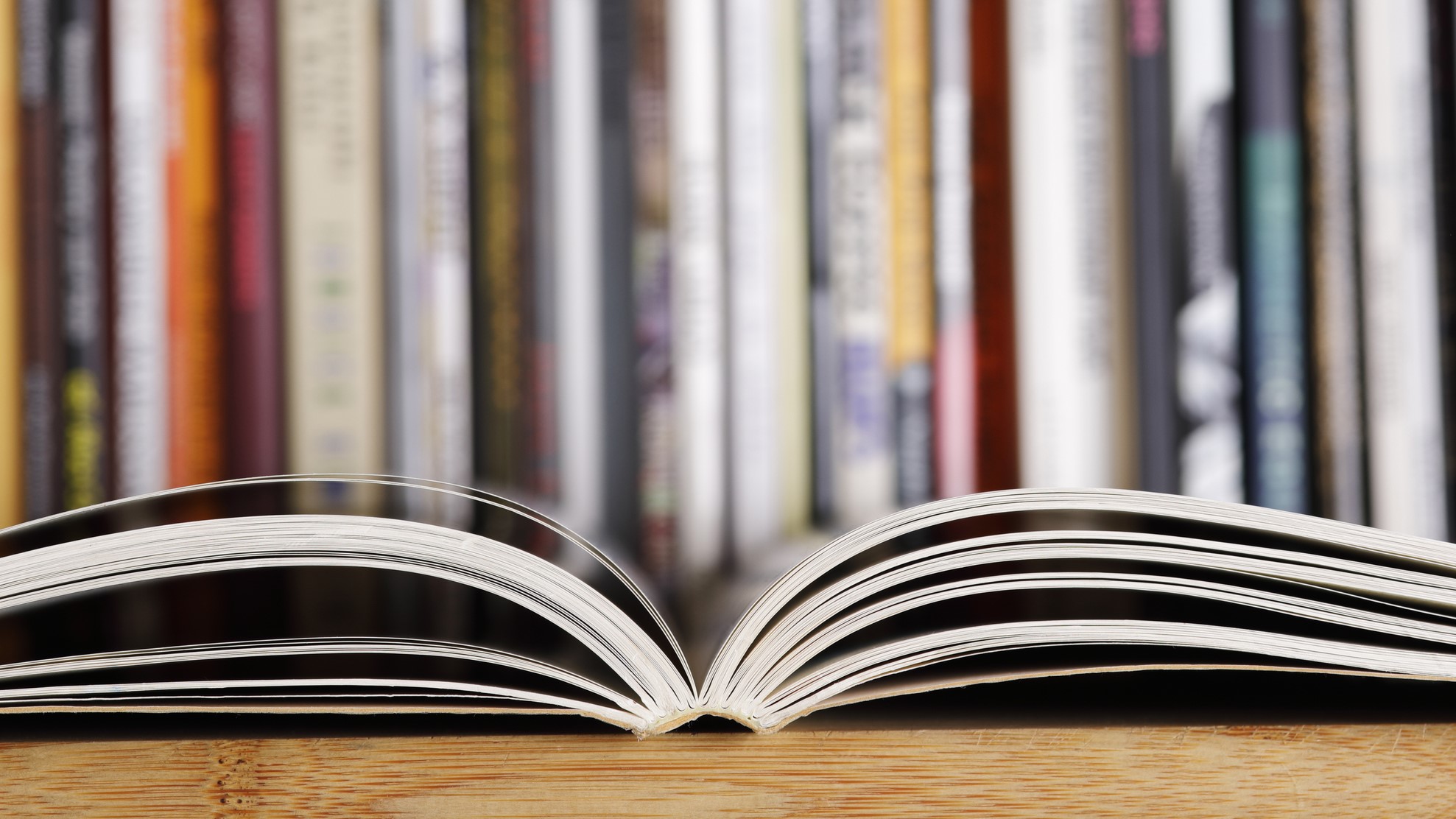 An open scientific journal in the foreground with many journals standing in the background