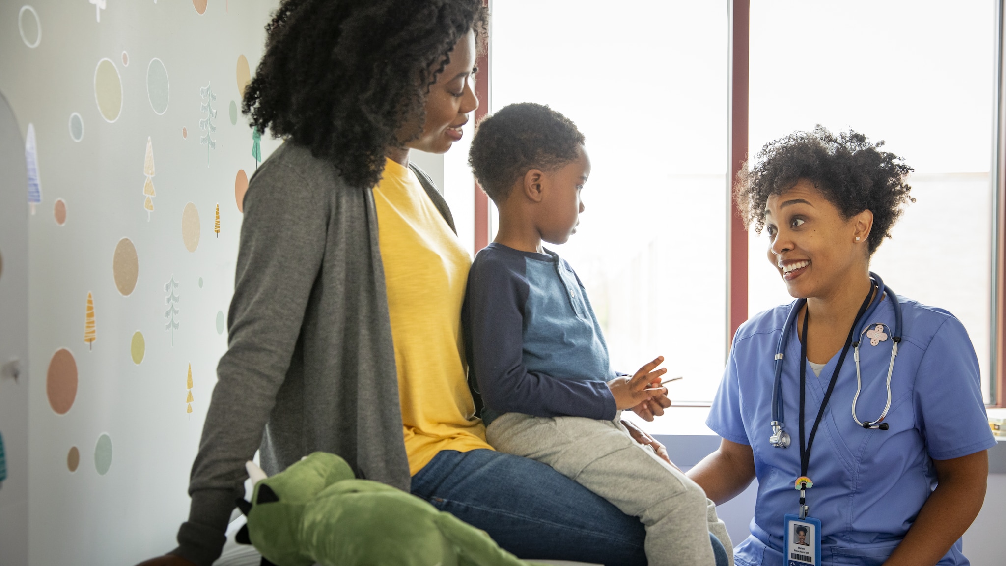 Child and parent sitting on an exam table talking with the doctor.