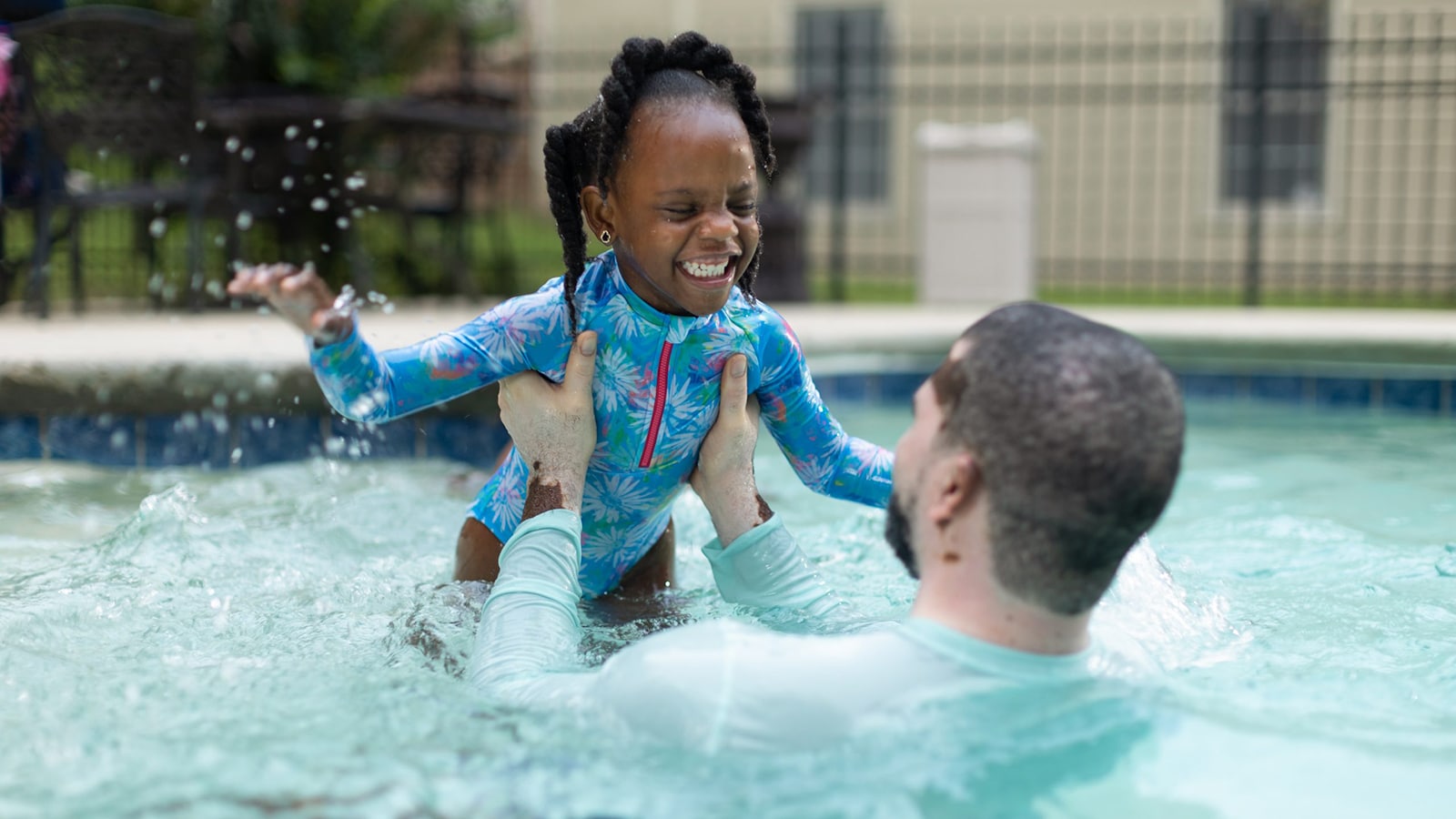 Father and daughter play in swimming pool.