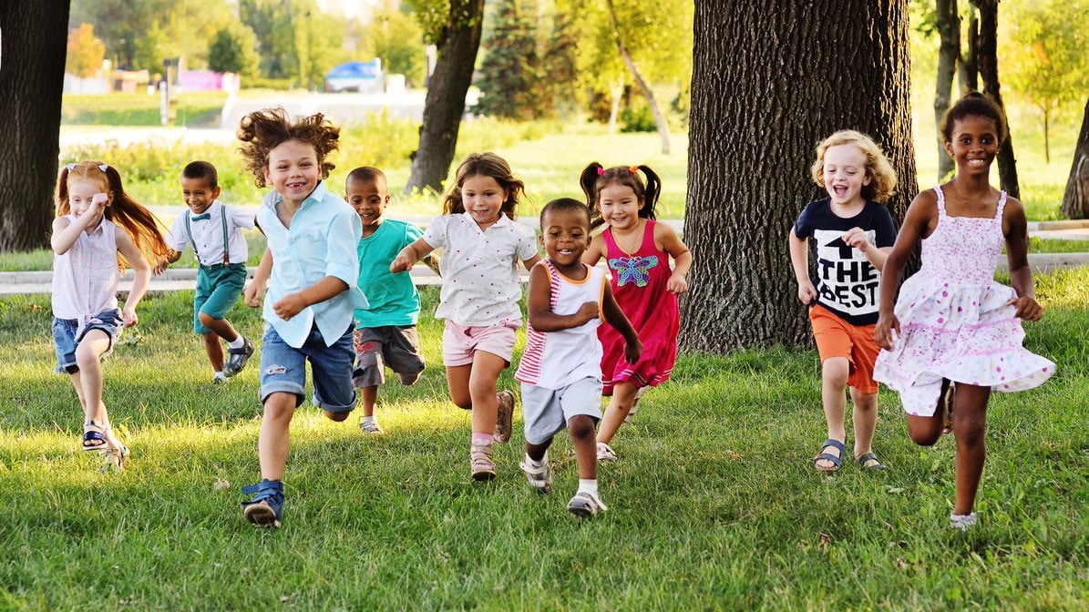 Group of young children running outside.