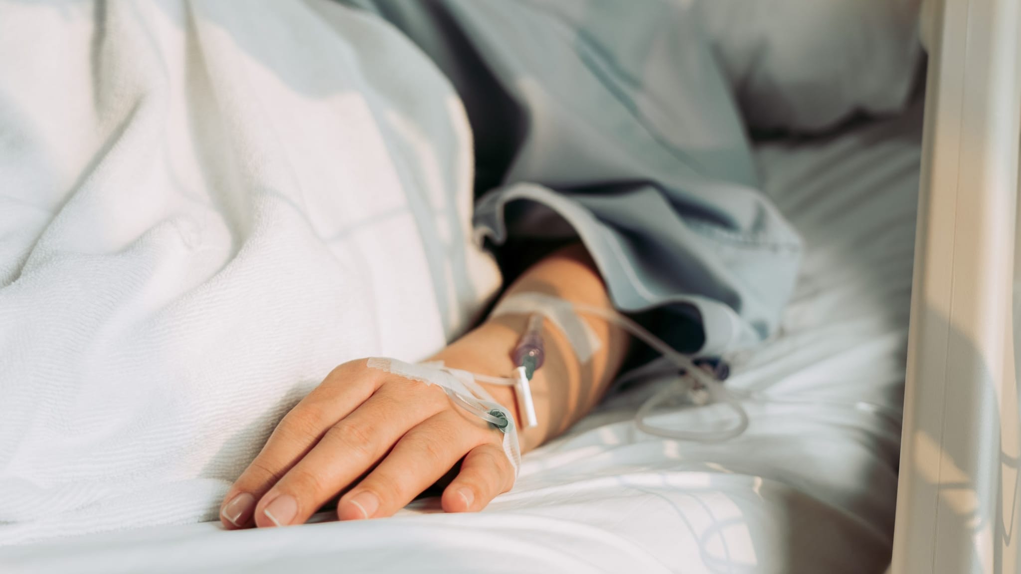 Hand with IV in a hospital bed