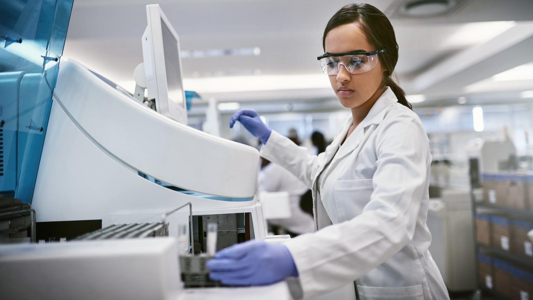 A lab worker in a white coat running tests in a laboratory.