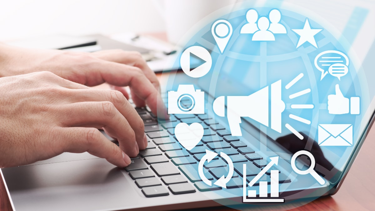 Focused view of a hands typing on a laptop with a pop-up icon array that shows different forms of social media channels and engagement