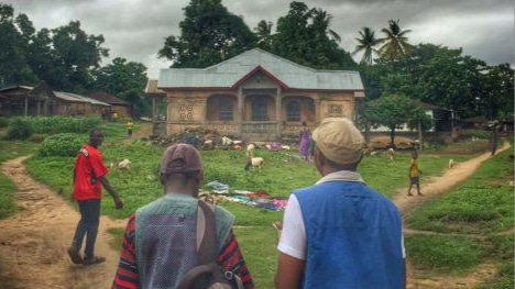 Two people walking along a splitting path in Sierra Leone and two other people ahead of them along both paths.