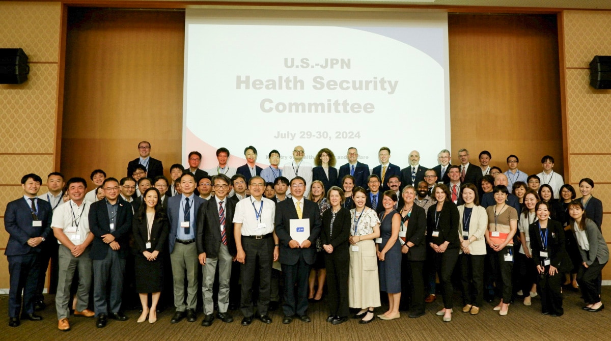 Group of meeting attendees in front of a sign that reads "US.-J Health Security Committee"