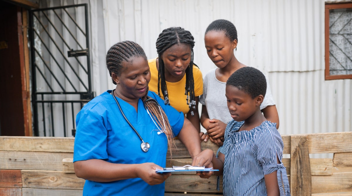 A nurse speaks to three children.