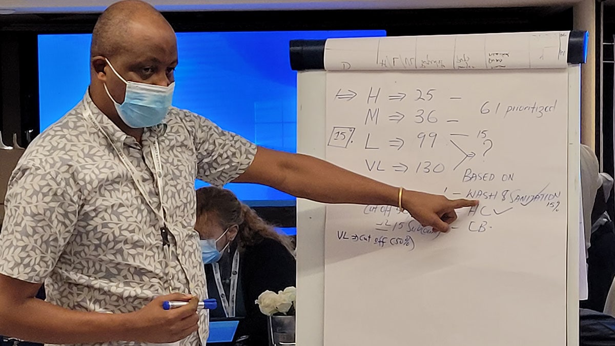 A man at a presentation board training people for oral cholera vaccination