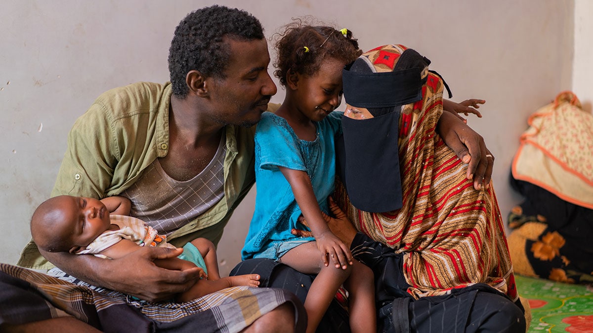 Three-year-old girl poses with her father, mother and sibling in Yemen.