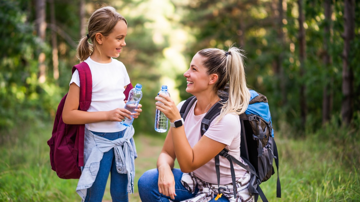 Mother and daughter drinking water while hiking