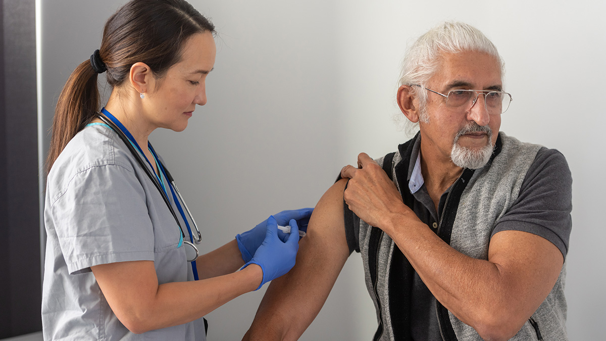 A healthcare professional giving a man a shot in his shoulder