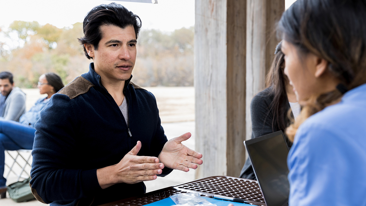 A man speaking with a healthcare professional outdoors