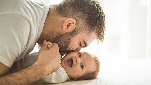 A father kissing the cheek of his infant.