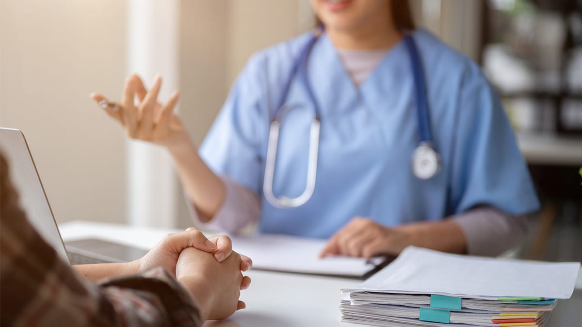 A doctor gestures while providing a medical consultation to a patient.