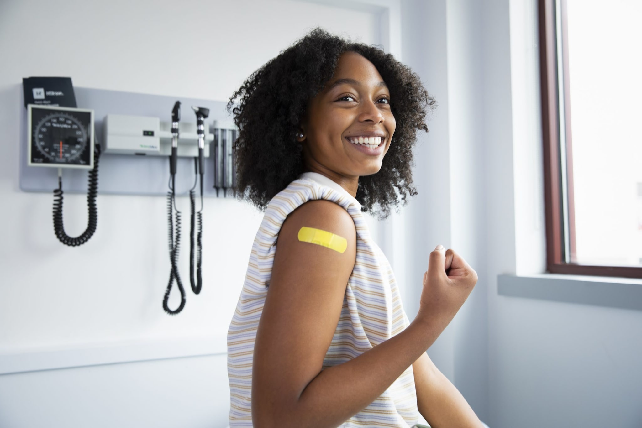 Adolescent girl smiling with a bandage on her arm.