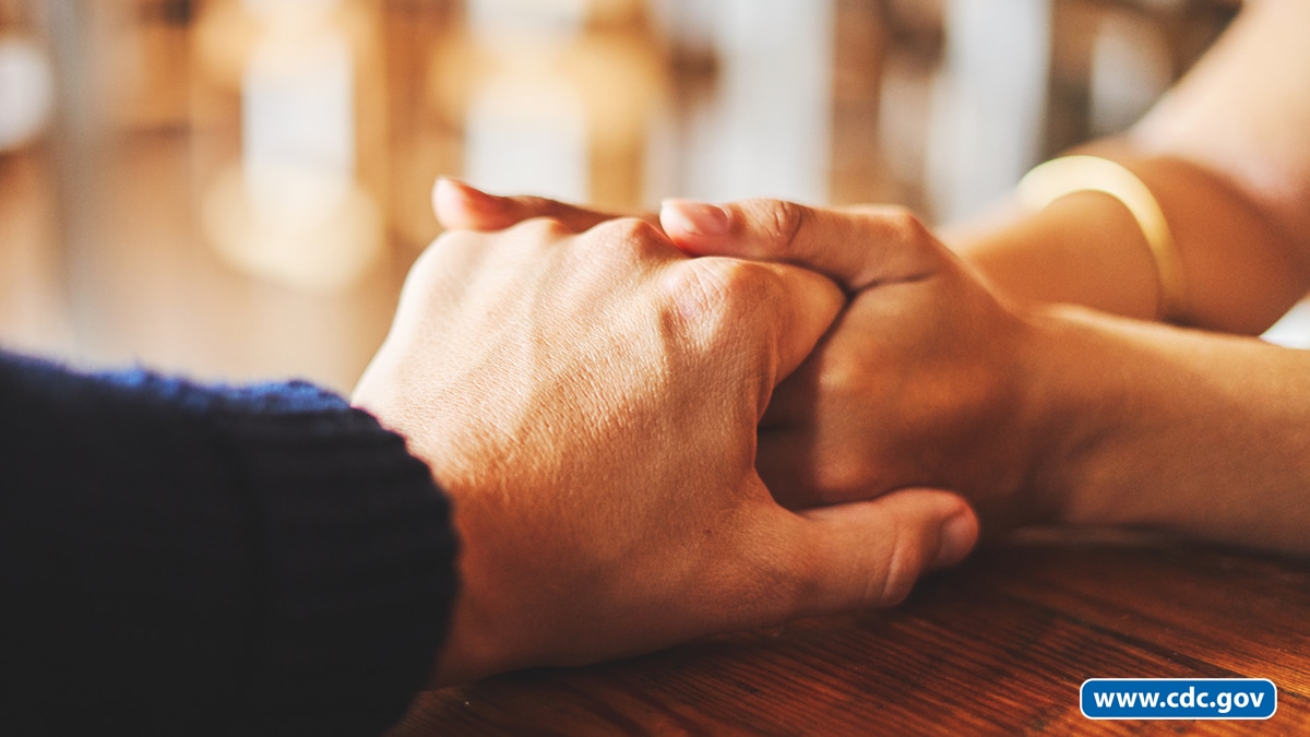 Two people hold hands in a supportive way