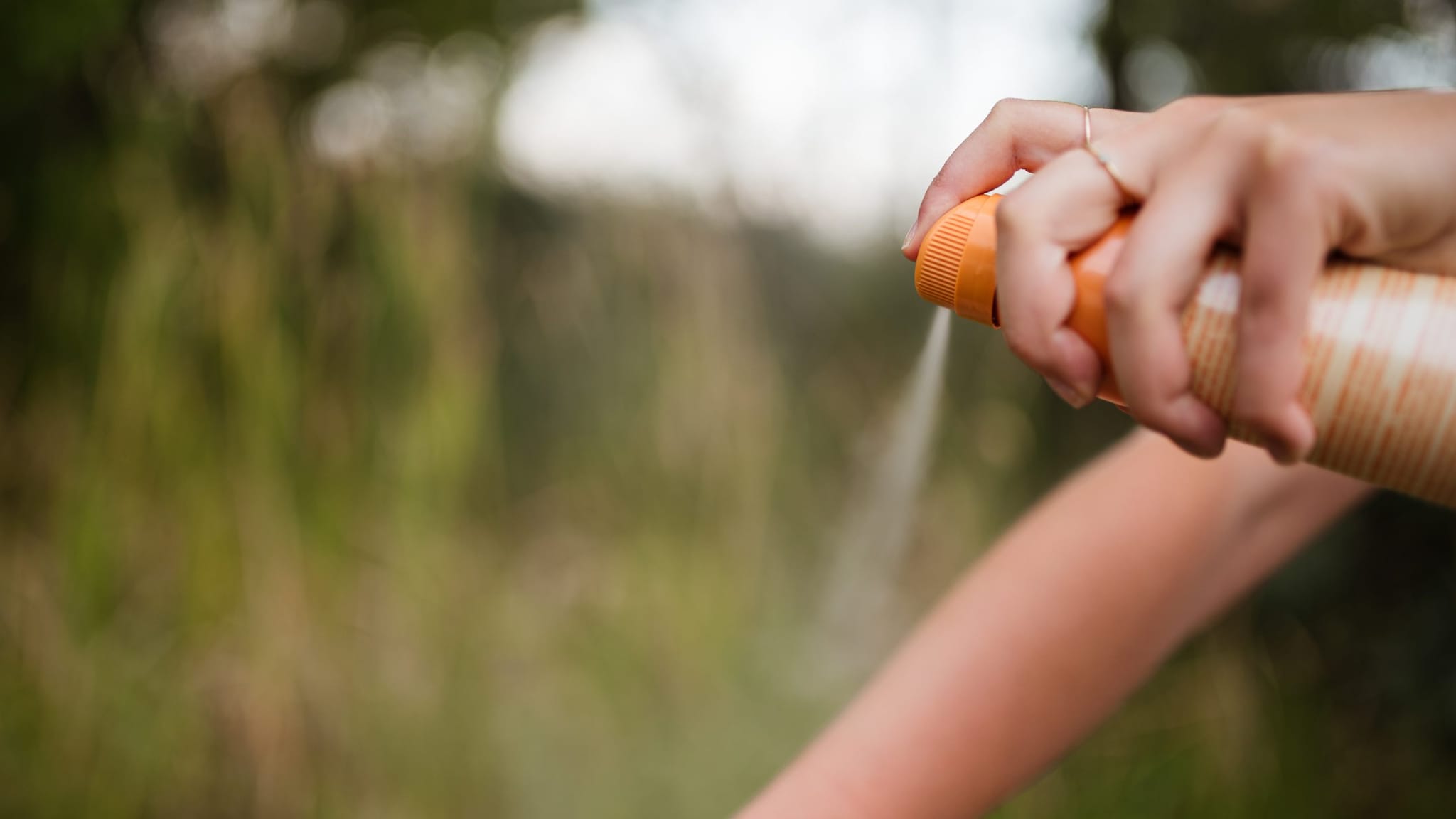 Person applying insect repellent to their arm.