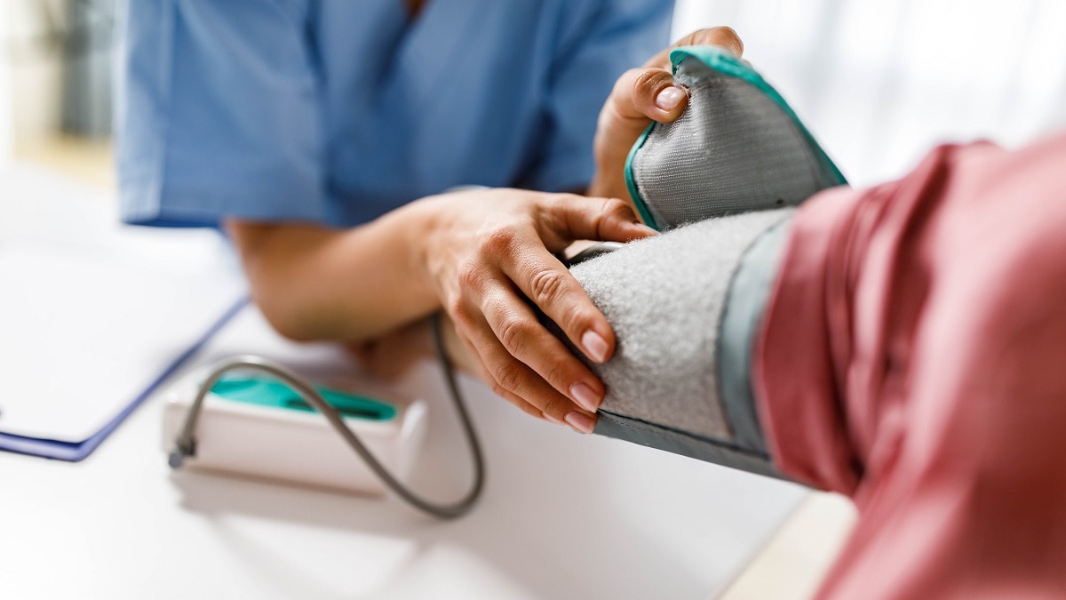 Nurse measuring blood pressure of a woman during a home visit.