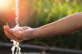 A child's hand catching water as it falls.