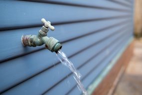 A faucet running water next to the panel of a house