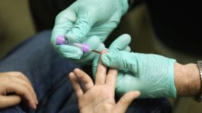 A health care provider using a finger-prick to find the blood lead level of a patient.