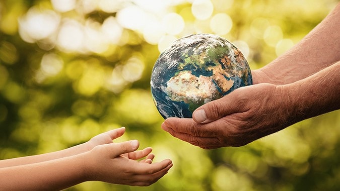 Senior hands giving small planet earth to a child