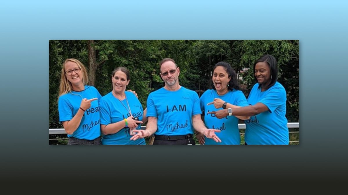 A group of women each with a shirt that reads I Beat Michael surrounding a man wearing a shirt that reads I Am Michael.