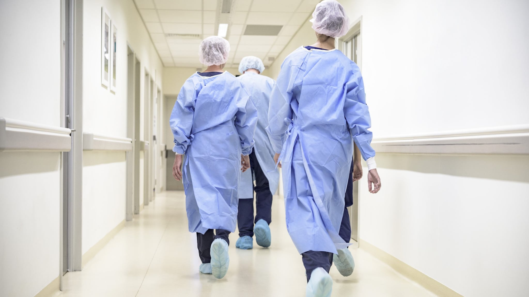 People wearing personal protective equipment walking down a hallway in a healthcare facility