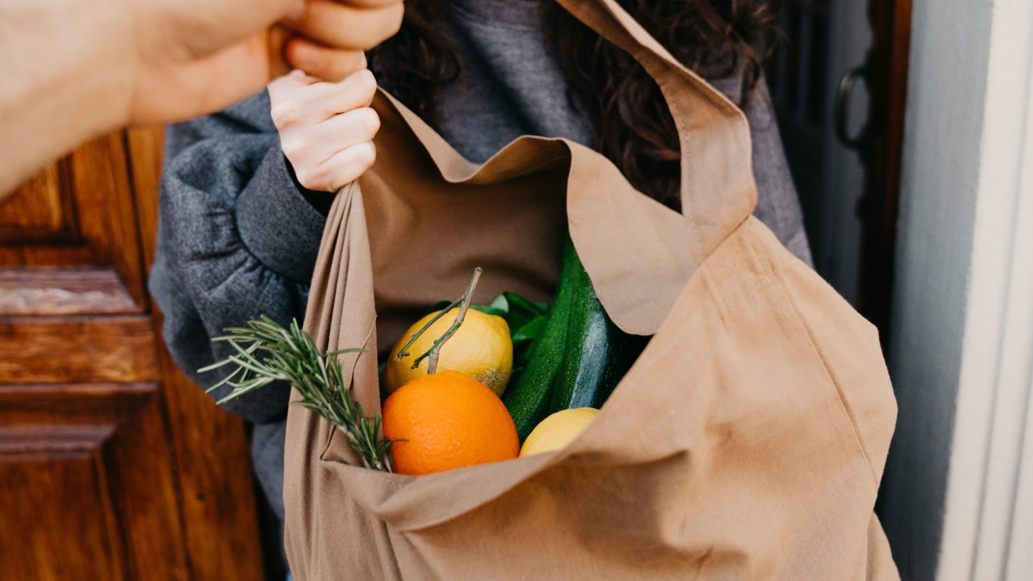 Bag of produce being delivered by hand.