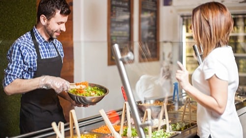 A person getting a salad at a worksite cafe.