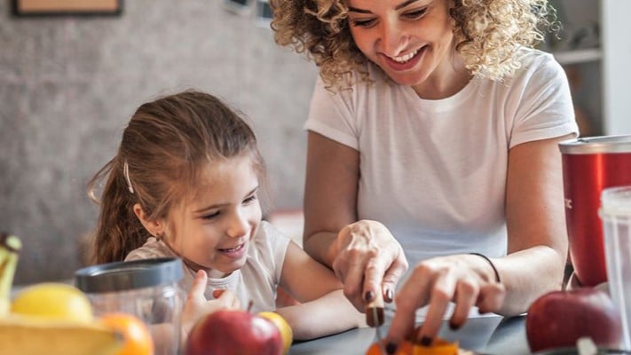 Woman and child cutting fruit.