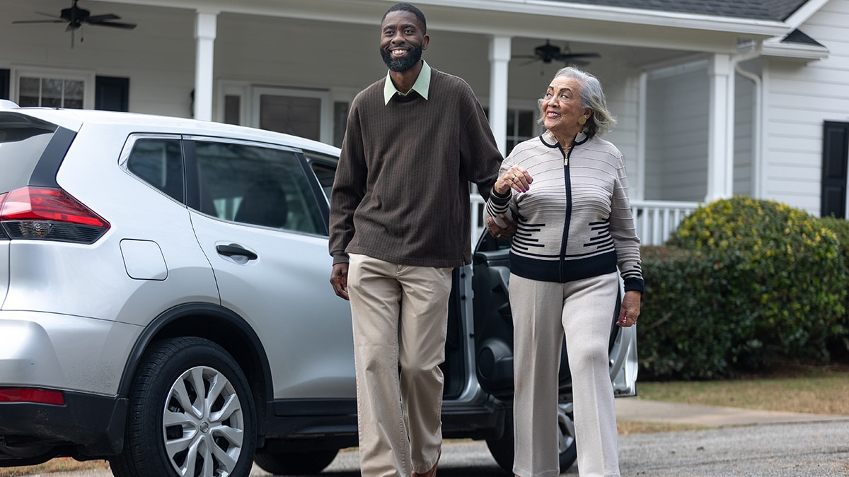 Man escorts older adult woman from car