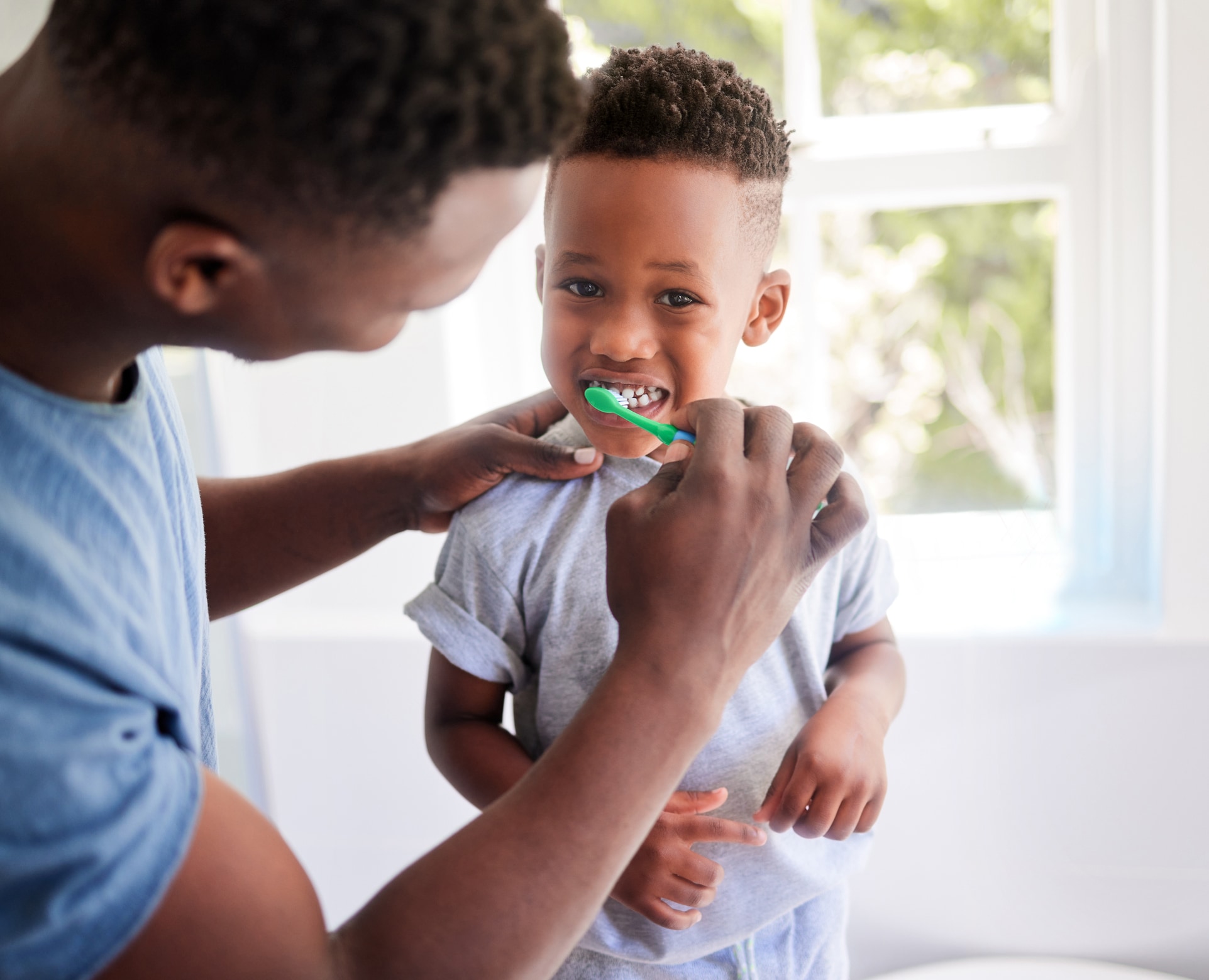 Man brushes child's teeth.