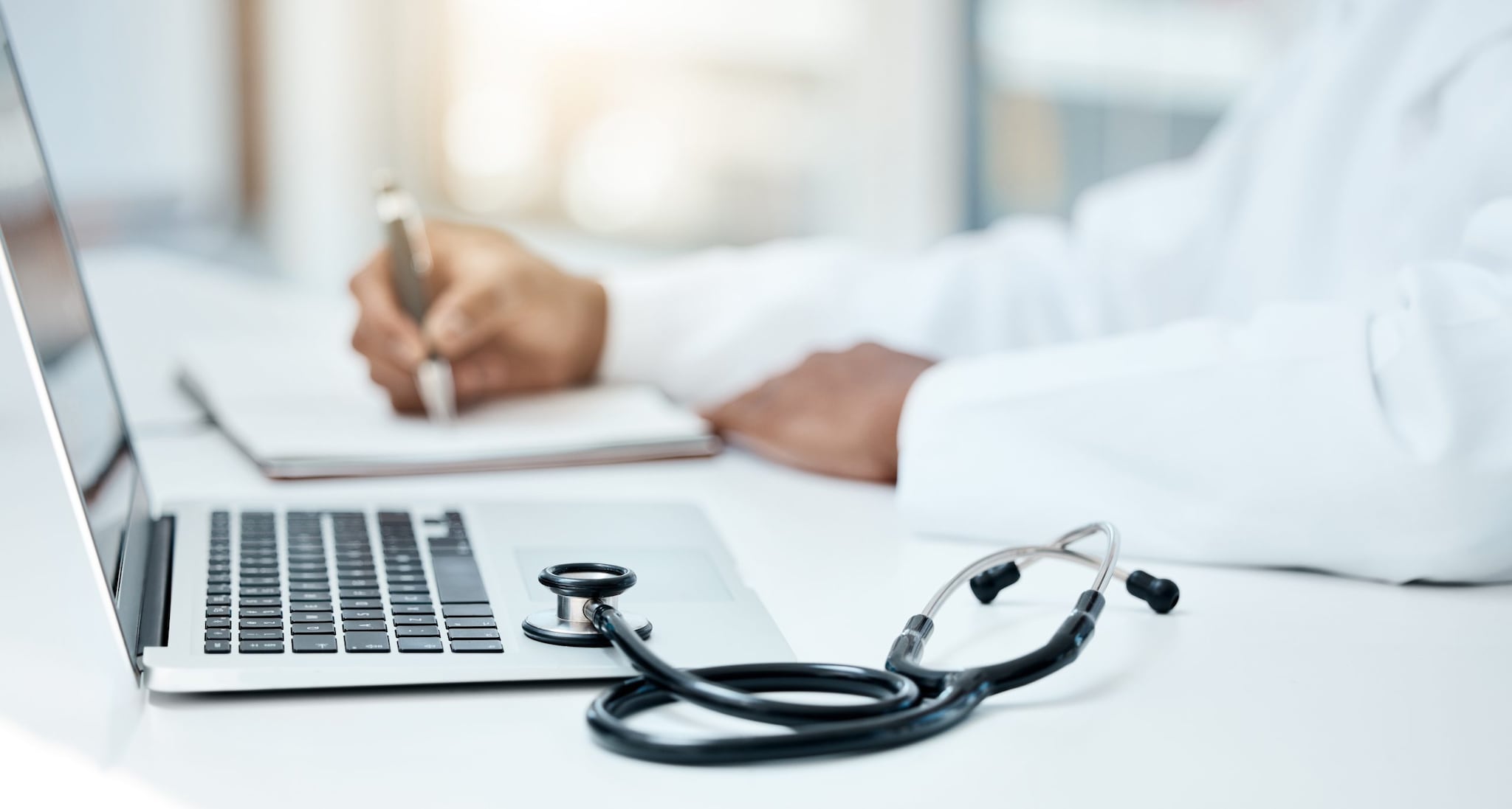 Clinician holding a pen and using a computer.