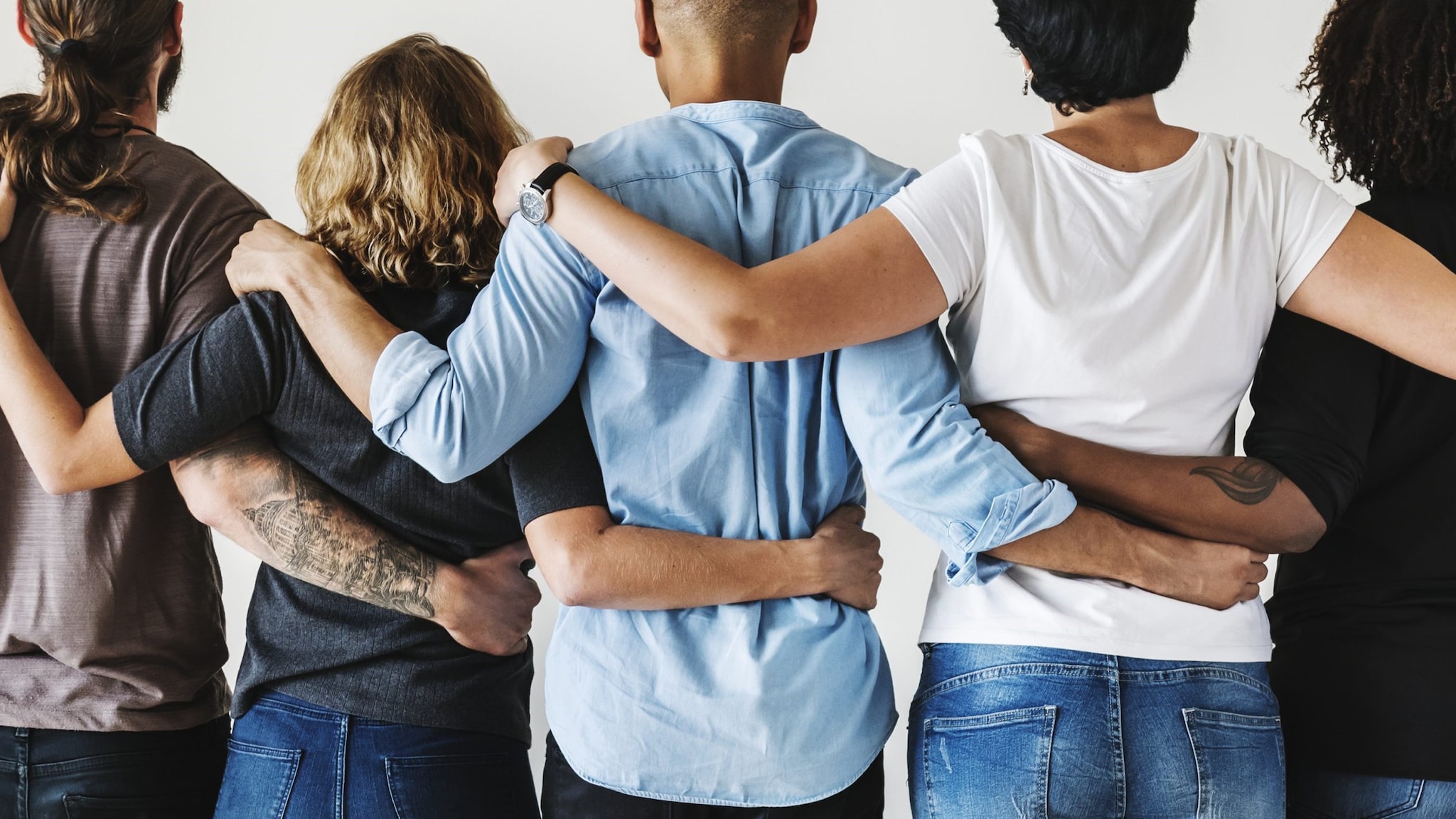 Five people with their arms around each others backs.