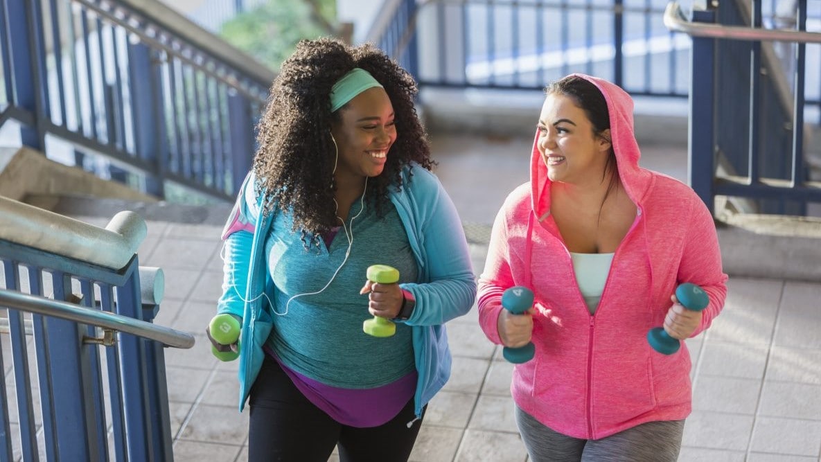 Two women walking up stairs and carrying hand weights