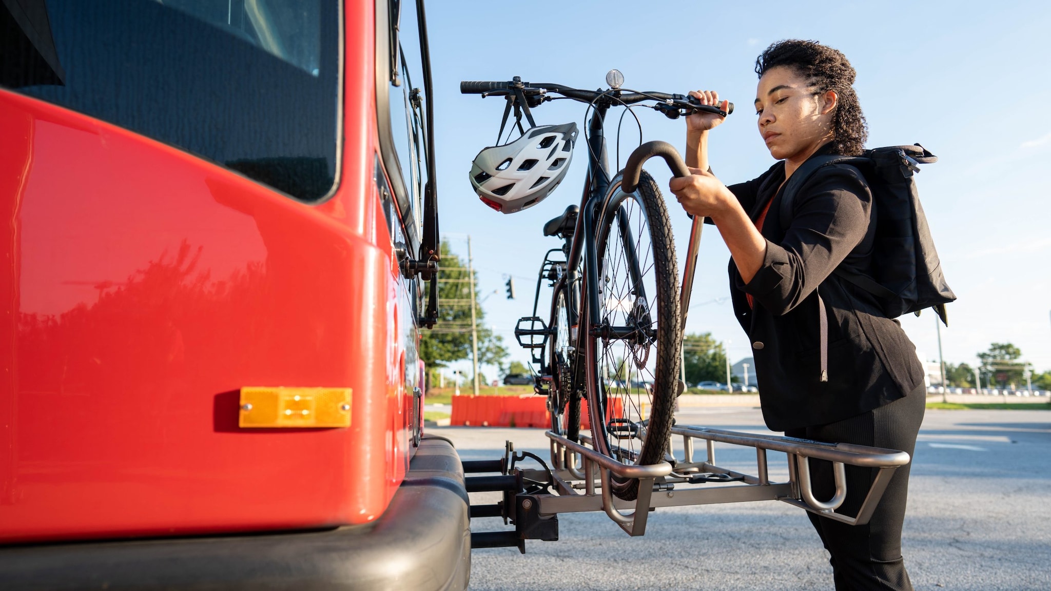 Woman loading bicycle onto bus.