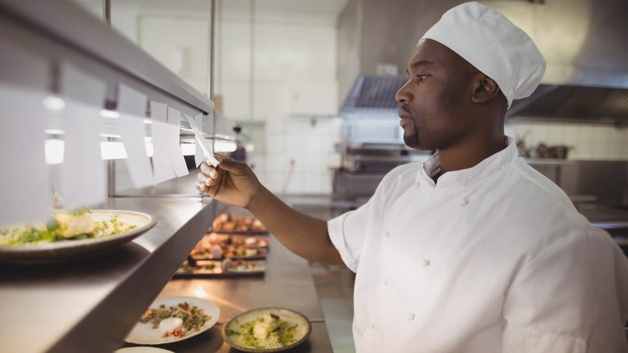 Chef looking at tickets and preparing food.