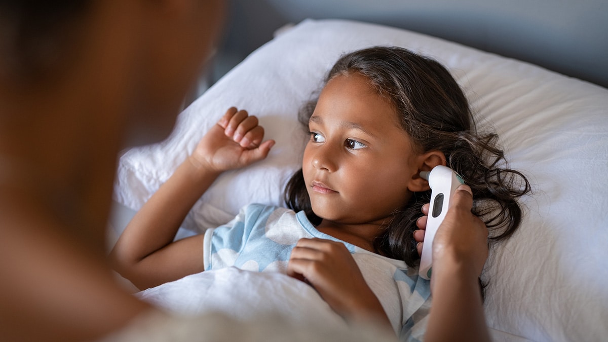 Mother checking daughter temperature with an ear thermometer.