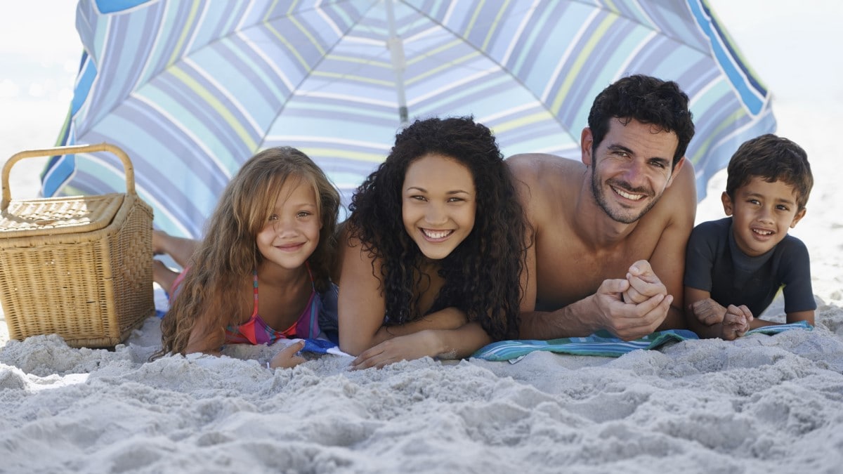 a family under a large umbrella on the beach